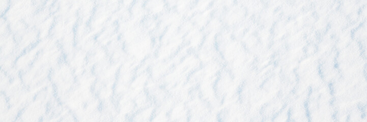 Obraz premium Wide panoramic winter background with snowy ground. Natural snow texture. Wind sculpted patterns on snow surface.