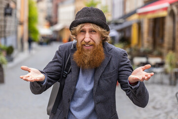 What. Why. Surprised frustrated young bearded man raising hands asking reason of failure,...