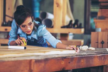 Attractive middle aged woman carpenter designer works with ruler, make notches on the tree in workshop. Image of modern femininity. Concept of professionally motivated women