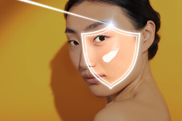 Sun protection care. Beautiful woman with sunscreen on face against golden background. Illustration of shield as SPF