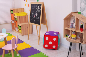 Stylish kindergarten interior with table, blackboard and toys