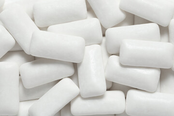 Tasty white chewing gums as background, top view