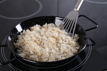 Cooking tasty rice on induction stove in kitchen, closeup