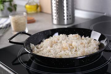 Cooking tasty rice on induction stove in kitchen, closeup