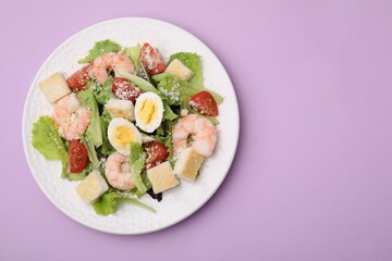 Delicious Caesar salad with shrimps on violet background, top view. Space for text
