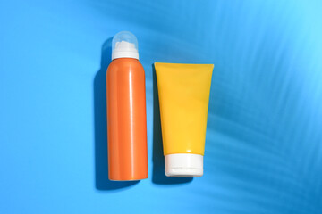 Sunscreens on light blue background, flat lay. Sun protection care
