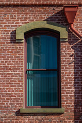 Green Facade and Window on a Red Brick Building Wall.