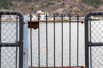 A wire railing fence and wrought iron gate overlook the water. The fencing is used to protect...