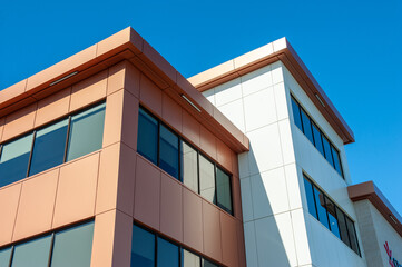 The roofs of a modern commercial building under blue sky and white clouds. The exterior of the new...