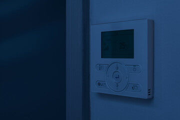 wall-mounted air-conditioning remote controller inside home or hotel at dark nighttime, room...