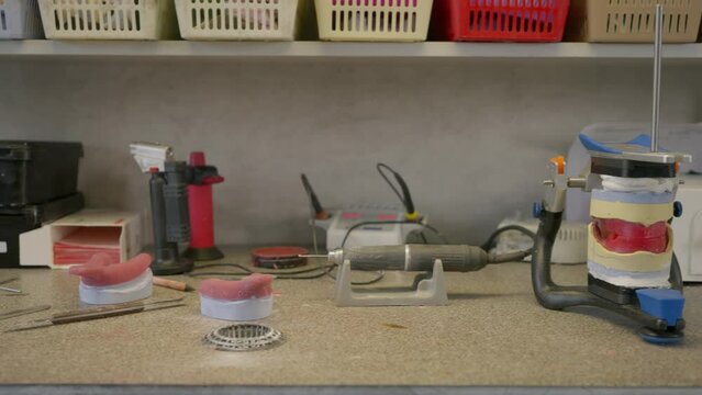 Producing the denture base dental appliance using the modern dentistry tools. Creating the artificial denture base with dentistry equipment. Handcrafting the denture base at the dentistry lab