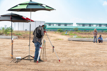 Surveyor worker with theodolite equipment makes measurements tachymeter and enters data.