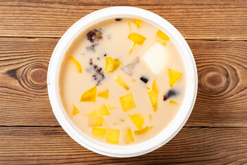 top view bowl of milktea flavor syrup mixed with grass jelly and mangoes and peach gum and tapiocas and red beans and guiling jelly etc. at horizontal composition
