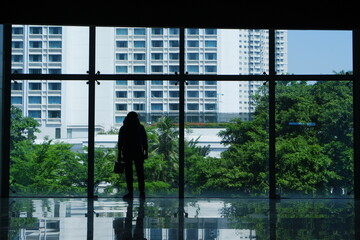 Jakarta, Indonesia, 19 July 2023 : A silhouette of a man with a backpack stands by a large glass...