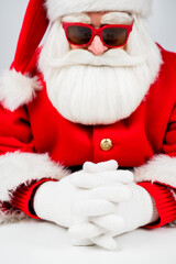 Portrait of santa claus sitting with his arms folded at a white table. 