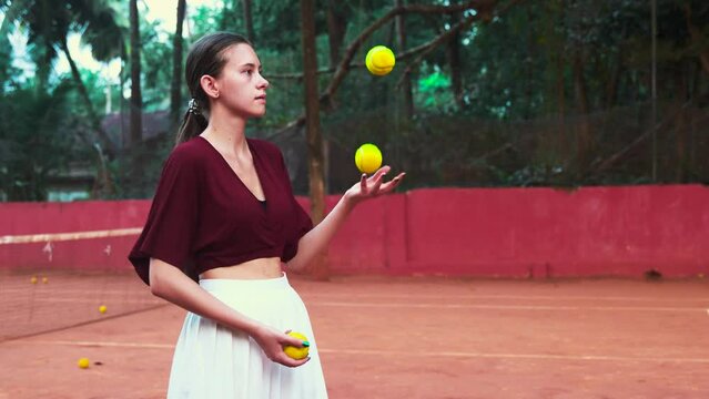 young woman juggling tennis balls in a white tennis skirt