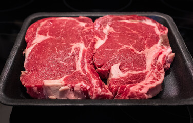 Beef steak. Fresh raw beef steak isolated on black background, top view. Raw rib eye steaks on styrofoam tray. Marbled beef raw meat steak. Nobody, selective focus