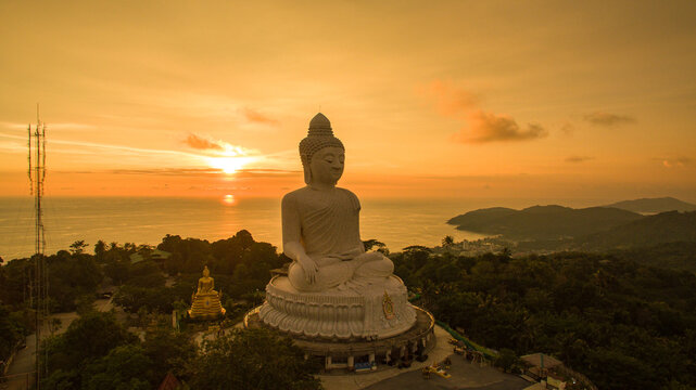 .aerial view Phuket big Buddha in beautiful sunset..amazing sun shines through the yellow clouds impact on golden sea surface.The beauty of the statue fits perfectly with the charming nature..