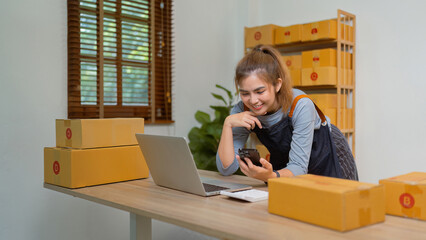 Young business woman working online ecommerce shopping at her shop. Young woman seller prepare parcel box of product for deliver to customer. Online selling, ecommerce