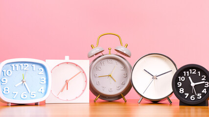 Close-up Front view, 5 alarm clocks on a pink background.