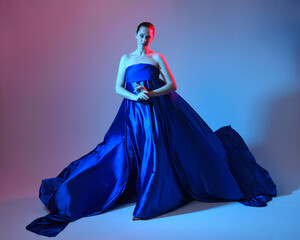 Full length portrait of beautiful female model wearing elegant flowing toga gown of blue silk...