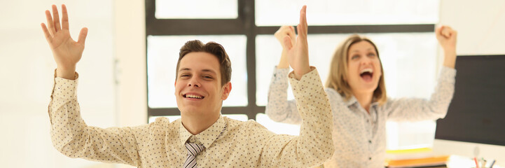 Fototapeta premium Business partners rejoicing and raising their hands up in office