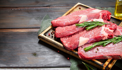 Raw meat. Raw beef steak on a cutting board with rosemary and spices.