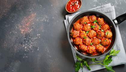 Meatballs in tomato sauce in a frying pan on dark stone table. Top view copy space.