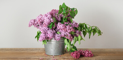 Metal bucket of beautiful lilac flowers on wooden table