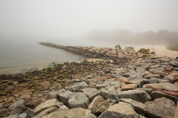 Rocky breakwater along a foggy beach in Niantic, Connecticut.