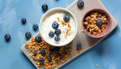 Greek yogurt granola and blueberries on blue table top view. Healthy food nutrition, snack or...