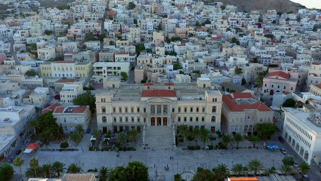 Aerial: Slow panoramic drone shot of Miaouli square and city hall building in Ermoupoli of Syros island, Greece during sunset