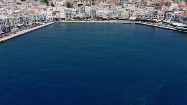 Aerial: Slow reveal shot of picturesque Emoupoli town of Syros island ,Cyclades, Greece
