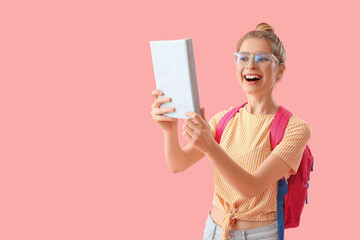 Happy female student with book on pink background