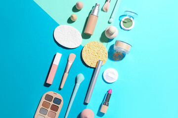 Decorative cosmetics with makeup brushes and sponges on color background