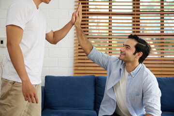 young handsome man giving hi five pose with his friends in a living room