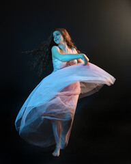 Full length  portrait of beautiful brunette woman dancer, wearing ethereal gown, dancing with...