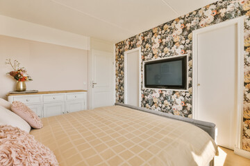 a bedroom with floral wallpaper on the walls, and a flat screen mounted tv in the corner of the room