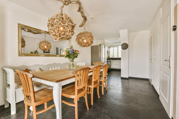 a dining room with wooden chairs and a large mirror hanging on the wall in the background is a white kitchen