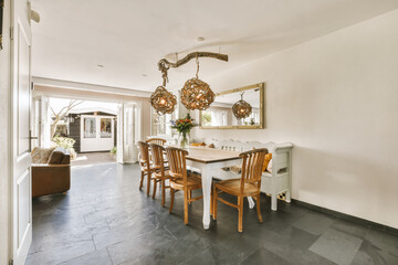 a dining room with white walls and black slate tiles on the floor, there is a large mirror hanging over the table