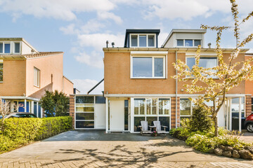 an outside view of a house with trees and cars parked in the driveway, on a sunny day - stock photo