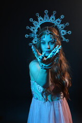 portrait of beautiful brunette woman wearing ornate silver crown headdress, posing with arm gestures, conjuring  magical spell. isolated on dark studio background, cinematic blue moonlight lighting.