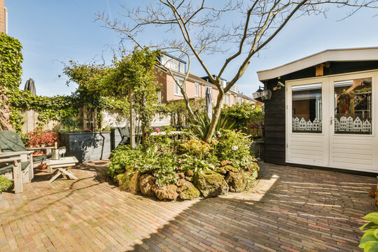 a backyard area with brick pavers and potted trees in the fore - image is taken from outside