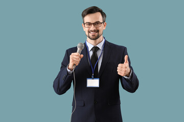 Male journalist with microphone showing thumb-up on blue background