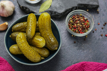 Bowl with tasty fermented cucumbers on dark grunge background