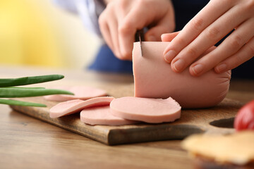 Woman cutting boiled sausage at table in kitchen © Pixel-Shot