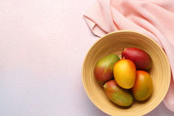 Bowl with fresh ripe mangoes on light background