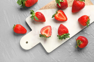 Board of fresh strawberries on grey background