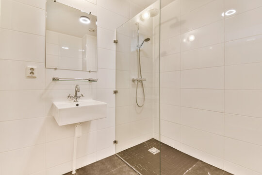 a modern bathroom with white tiles and marble flooring, including the sink and mirror in the corner shower stall