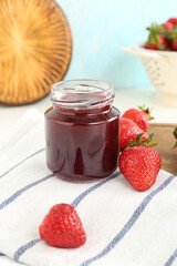 Jar of sweet strawberry jam on table